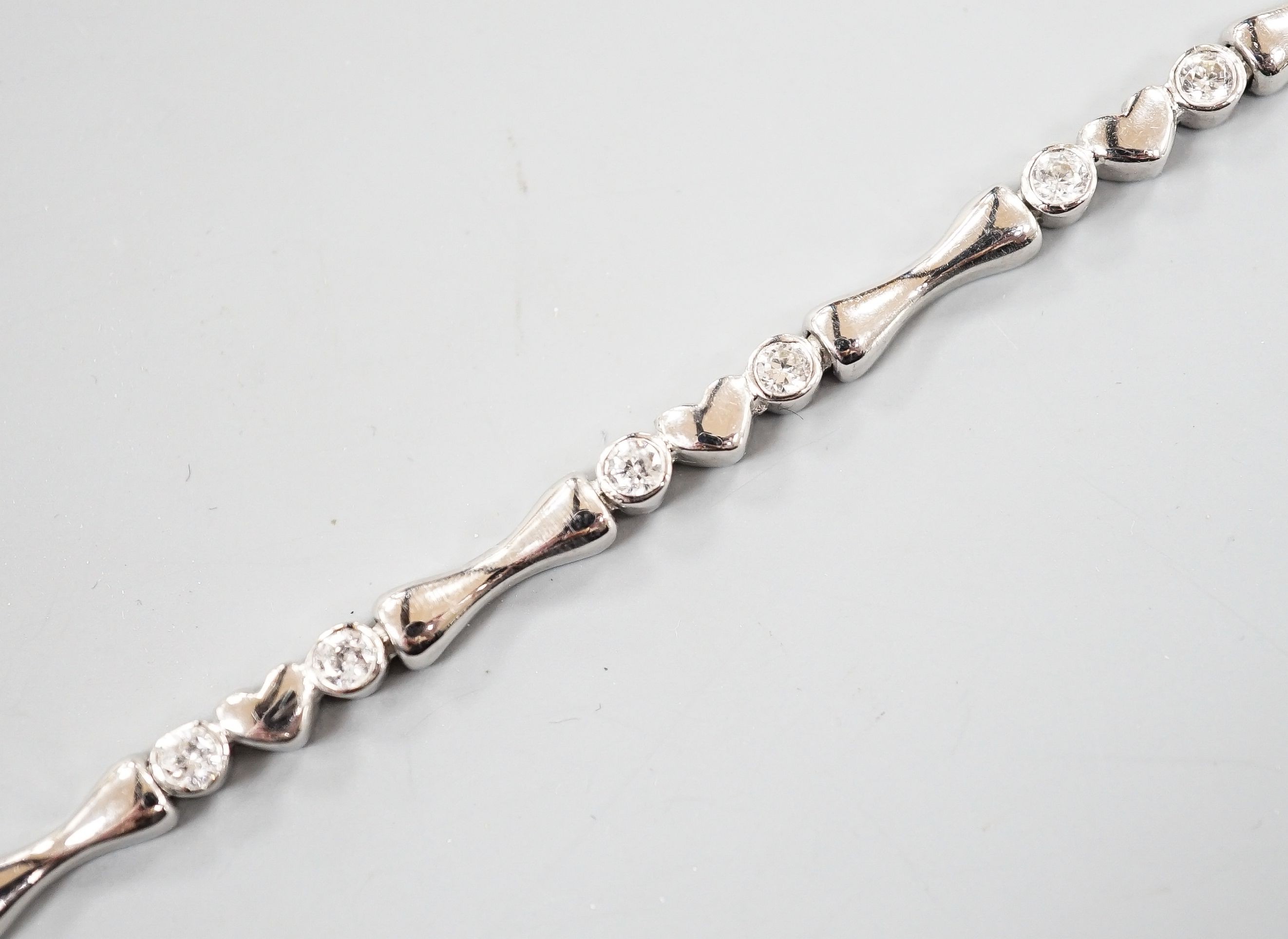 A modern 750 white metal and sixteen stone diamond set line bracelet, 19.2cm, gross weight 12.9 grams.